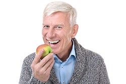 Middle-aged man in grey sweater eating an apple
