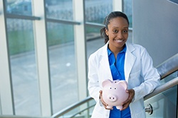 Syracuse implant dentist smiles and holds piggy bank