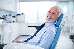 Older man wearing a tie smiling in the dental chair