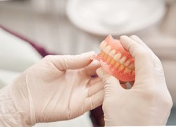 Close-up of gloved hands holding dentures in Syracuse, NY