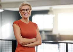 Senior woman with glasses smiling with arms folded