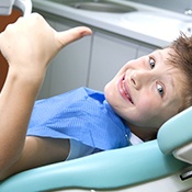 Smiling little boy in dental chair giving thumbs up