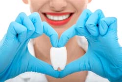 Syracuse general dentist holding model tooth with fingers in heart-shape