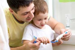 Father teaching son good children’s dental care in Syracuse