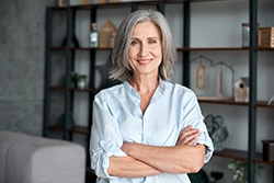 Woman with greying hair smiling with her arms crossed