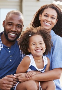 Father, mother, and child smiling together outside