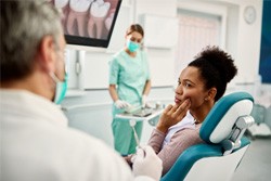 woman touching her face in dental pain talking to the dentist 