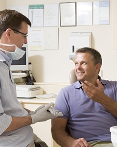 Smiling man in dental chair talking to dentist