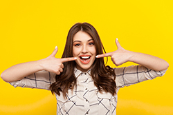 smiling woman pointing to her whitened teeth